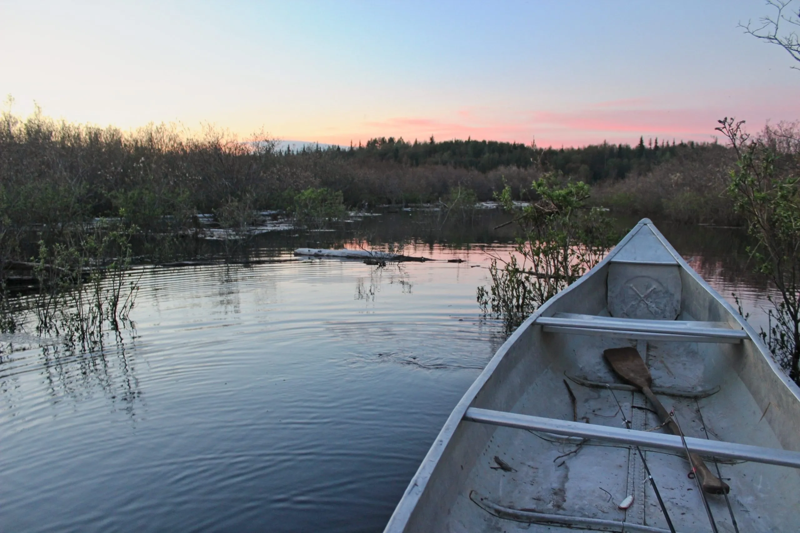 Canoe bow with fishing rods on Kako Lake at a midnight sunset in Alaska.