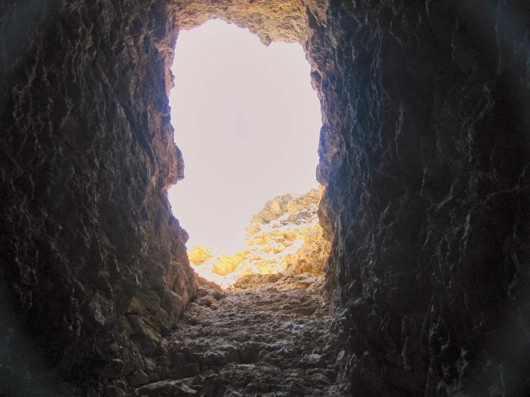 Sunlit rocky hillside framed by the dark opening of a mine tunnel at Giant Ledge Mine.