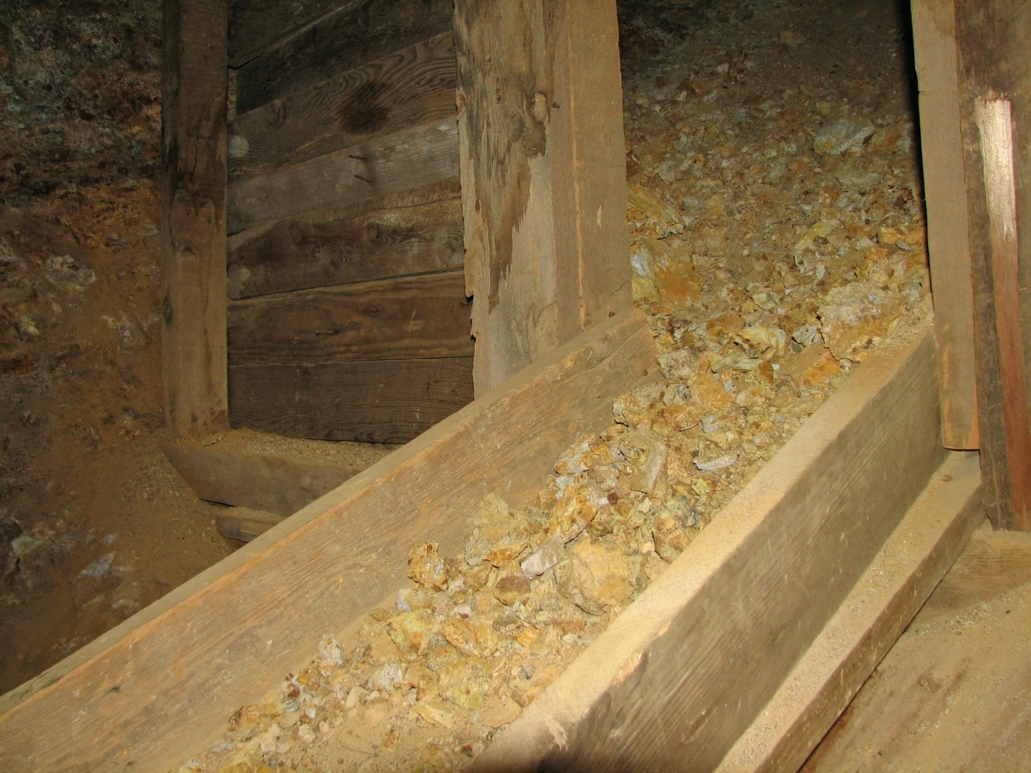 Wooden ore chute filled with gravel between timber supports inside Giant Ledge Mine.