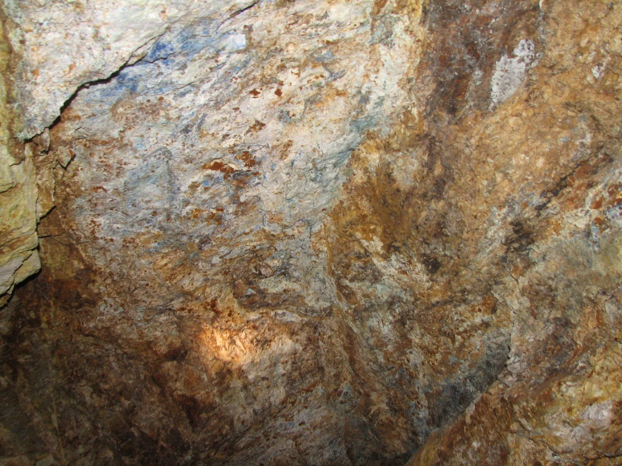 Close-up of blue and green copper mineral deposits on a mine tunnel wall.