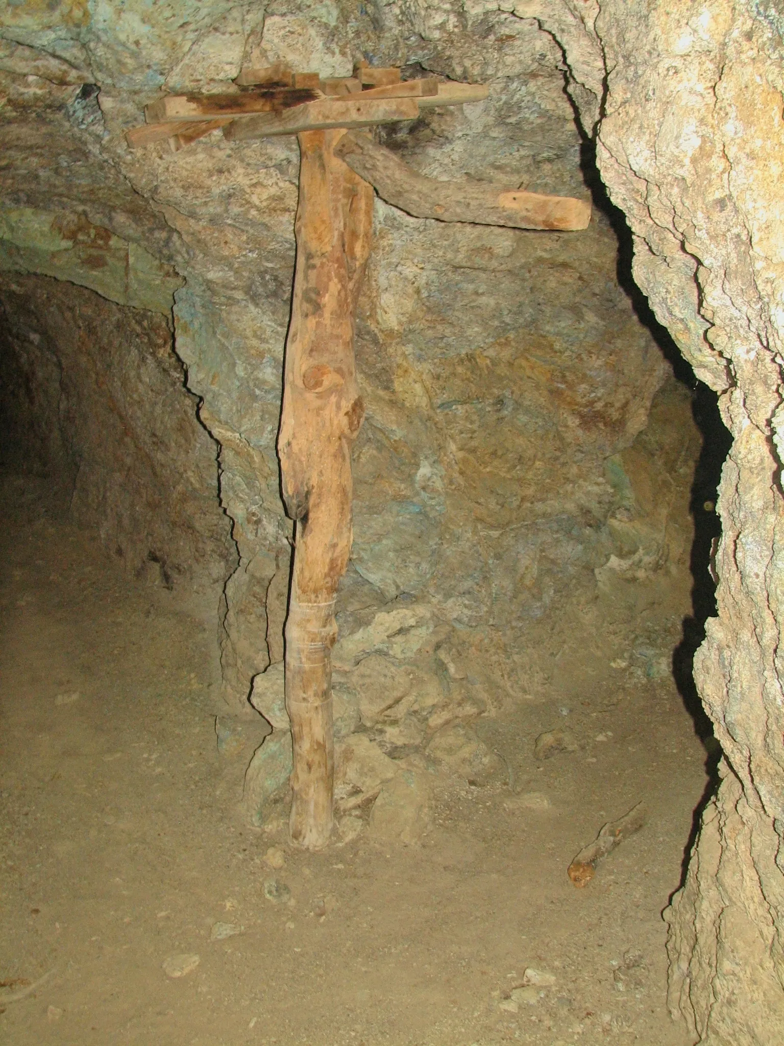 Rough-hewn wooden support post wedged against the ceiling of a mine tunnel.