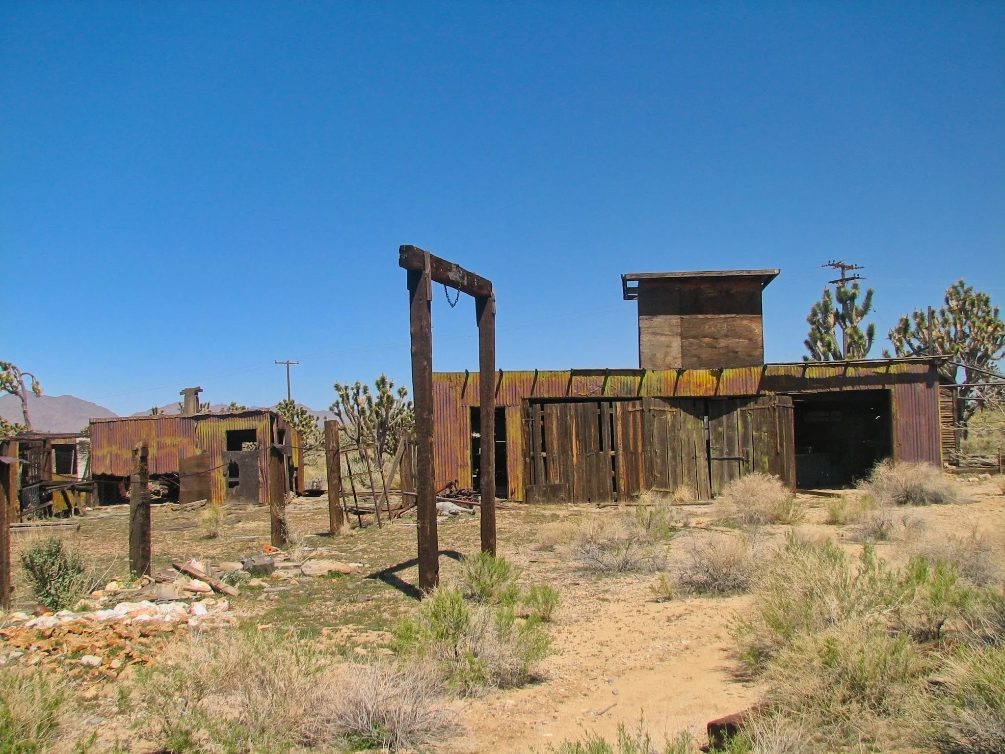 Weathered mine structures and a wooden frame with hanging chain at Death Valley Mine.