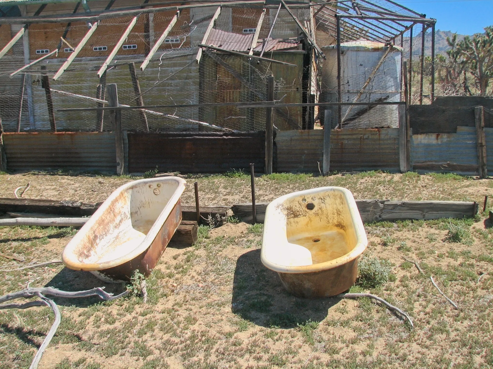 Two rusted bathtubs outside ruined mine buildings and a water tank at Death Valley Mine.