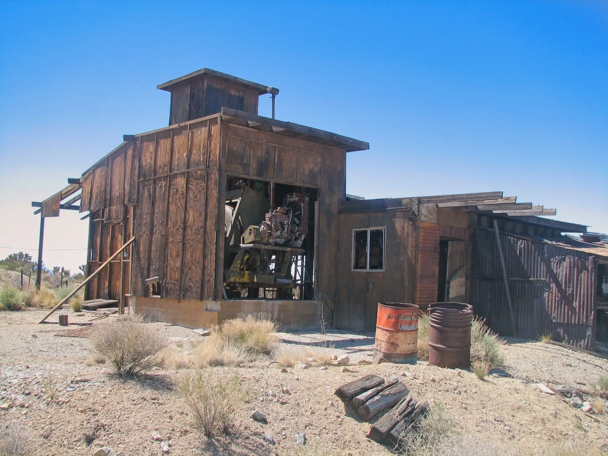 Weathered wooden mine building with exposed machinery visible through a large opening.