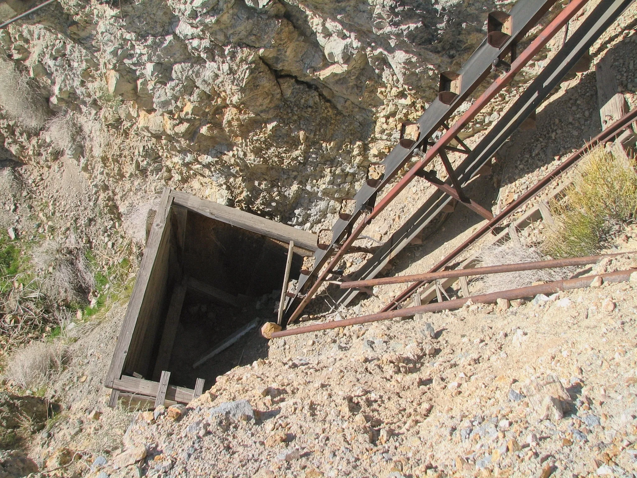 Timber-framed mine shaft with bucket elevator and metal tracks.