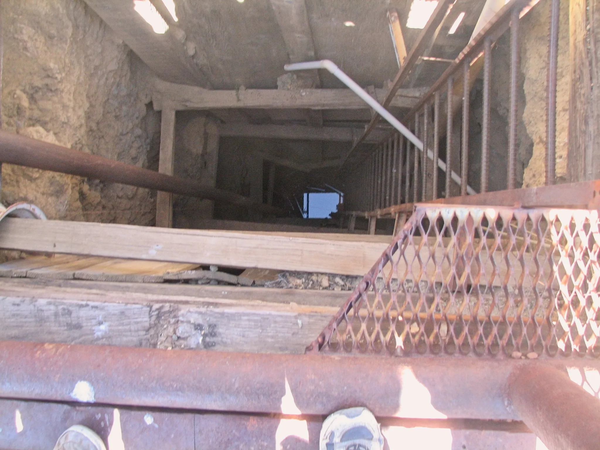 Looking down a timber-lined mine shaft with water at the bottom.