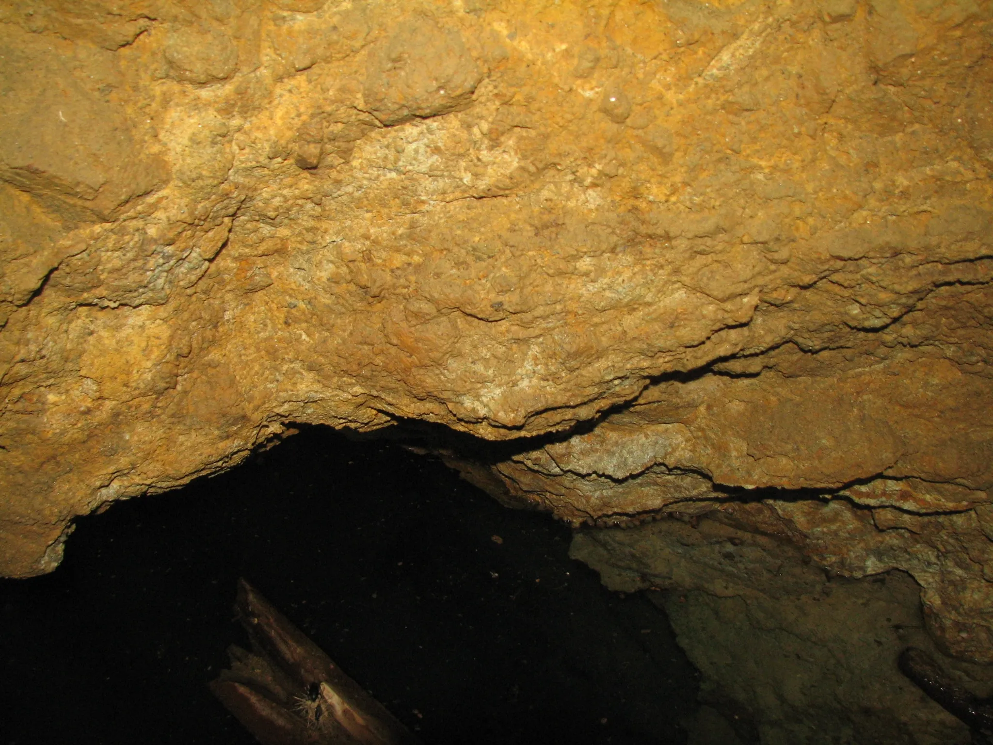 Jagged rock ceiling inside a mine tunnel illuminated by flash.