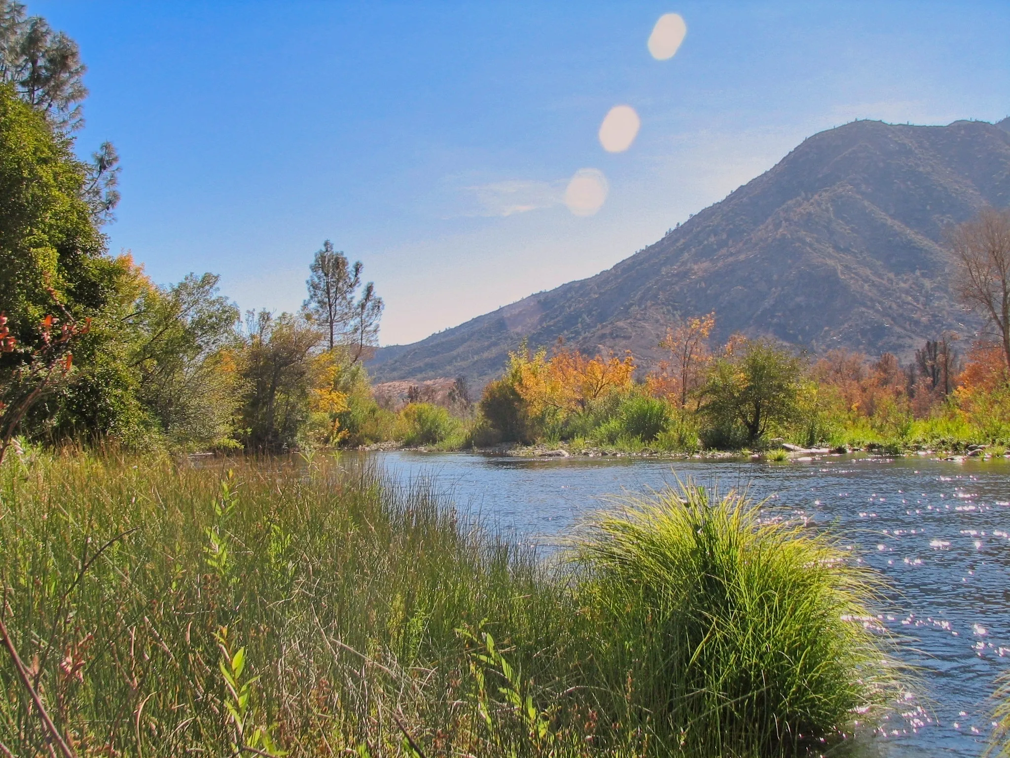 Kern River white water rushing over boulders through a canyon toward distant granite peaks.