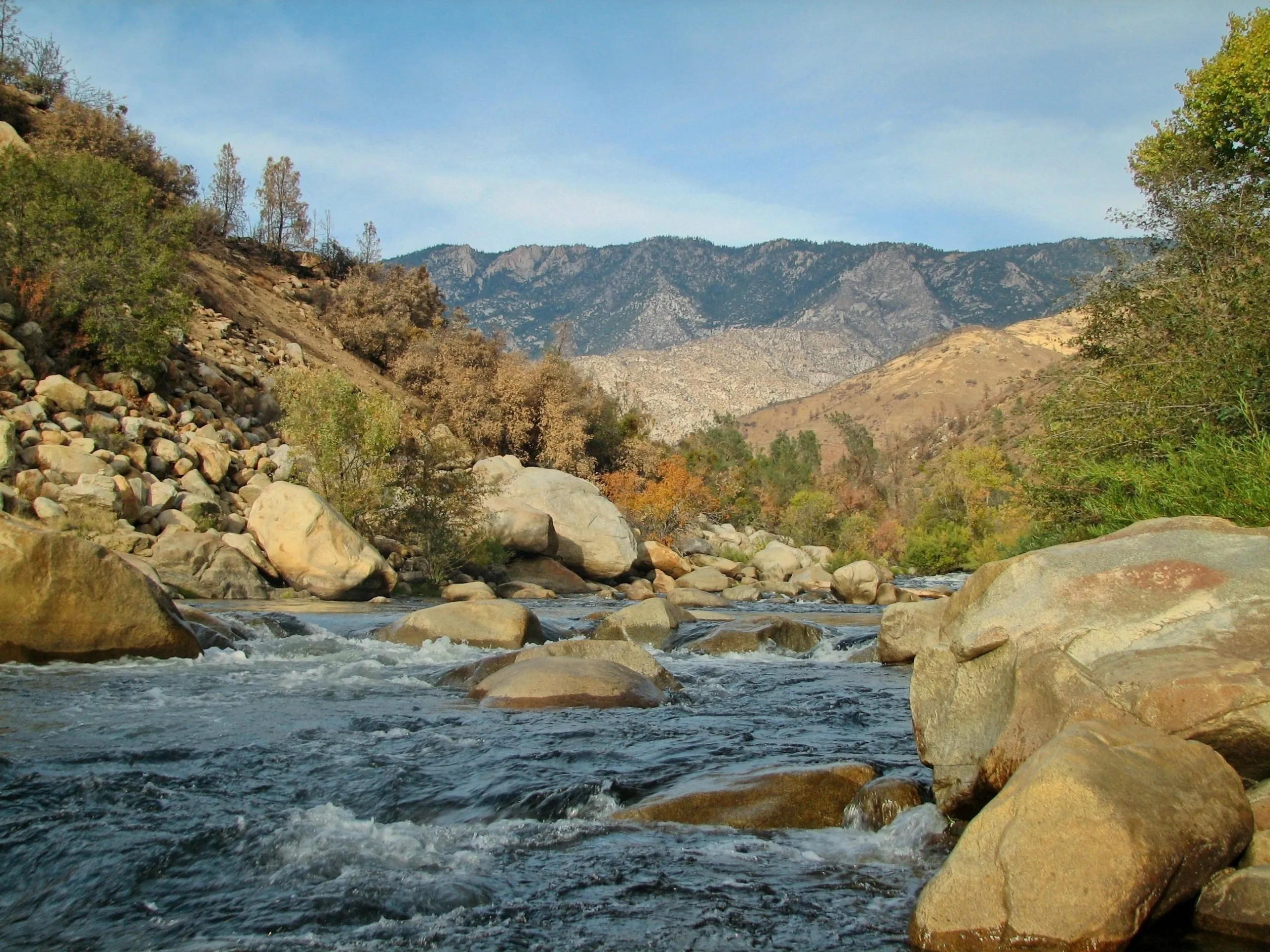 Kern River white water rushing over boulders through a canyon toward distant granite peaks.
