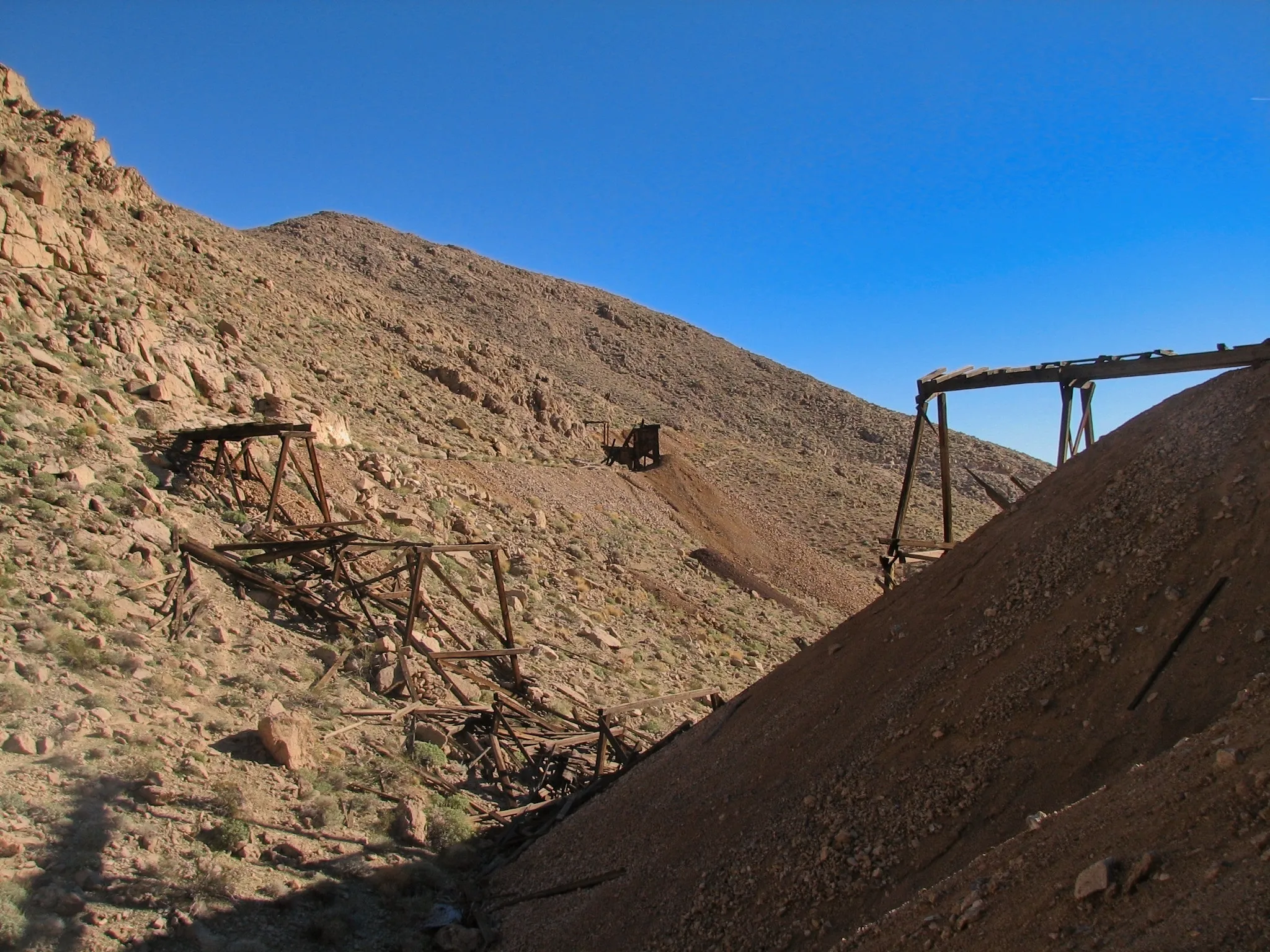 Scattered wooden mine ruins and tailings on desert hillside at War Eagle Mine.