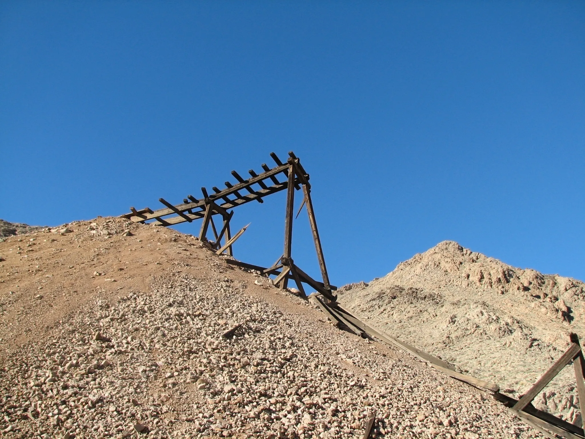 Dilapidated wooden headframe on gravel tailings pile at War Eagle Mine.