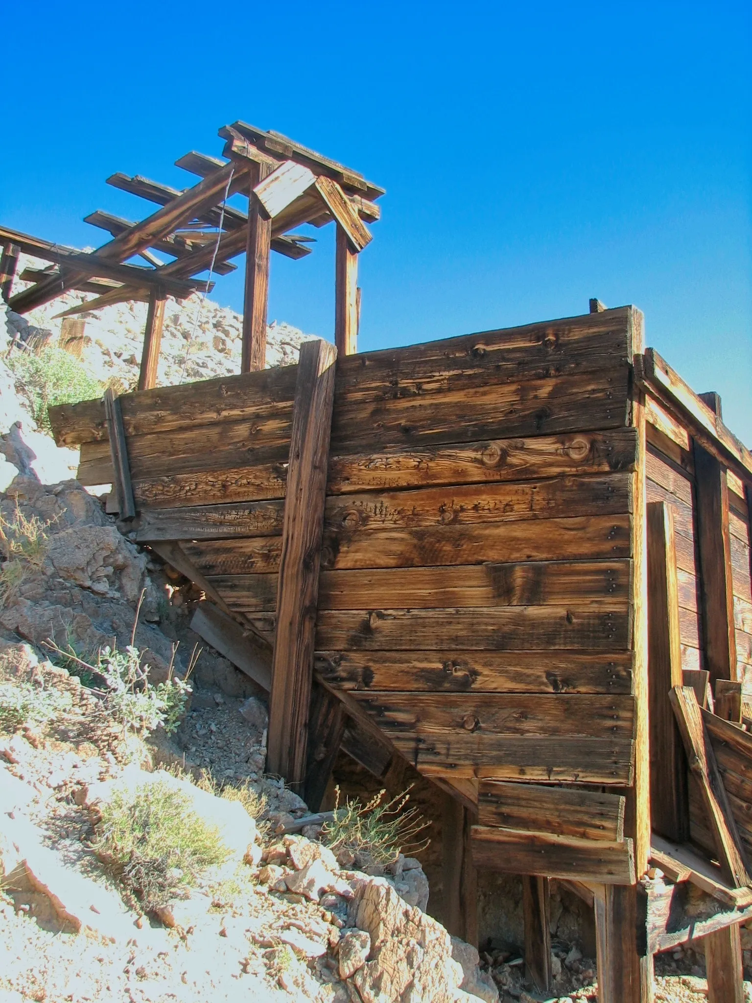Wooden mine structures and rusted mining equipment at the War Eagle Mine, Mojave Desert, California.