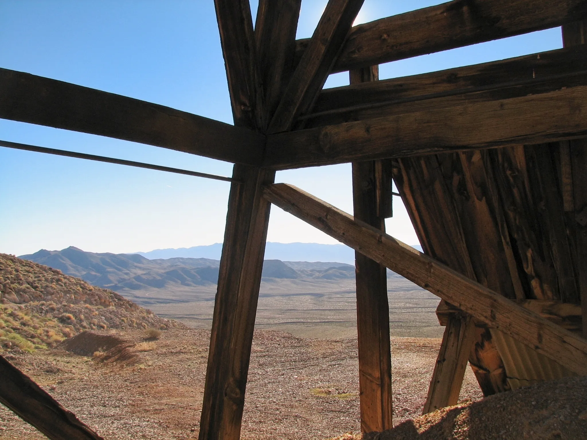 Wooden mine structures and rusted mining equipment at the War Eagle Mine, Mojave Desert, California.