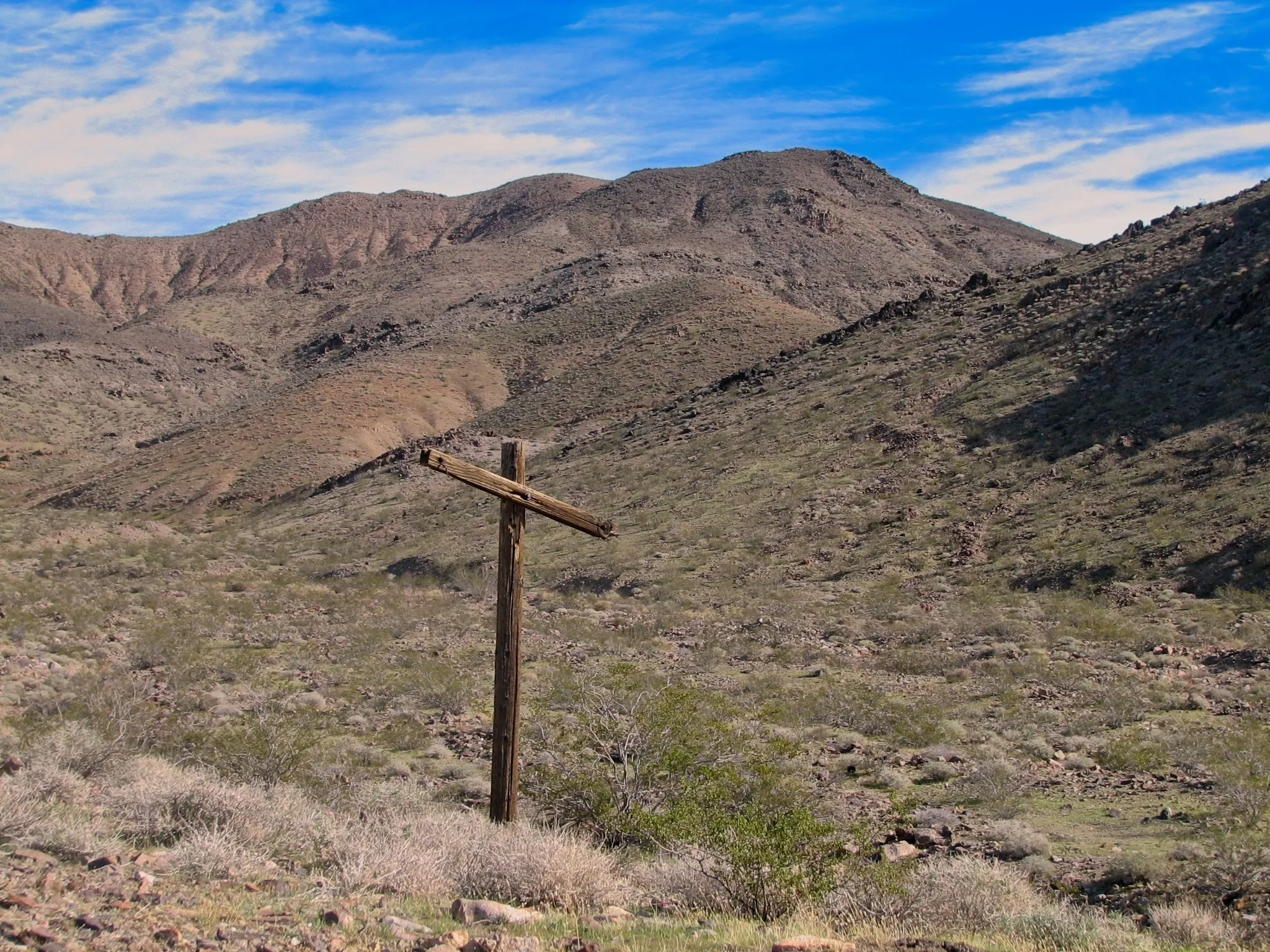 Weathered utility pole alone in desert valley with mountain backdrop.