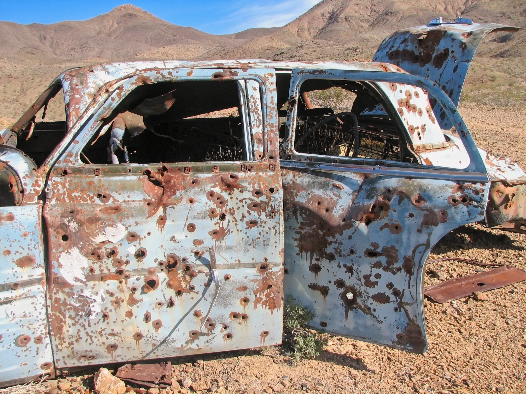 Bullet-riddled abandoned sedan in desert near War Eagle Mine.