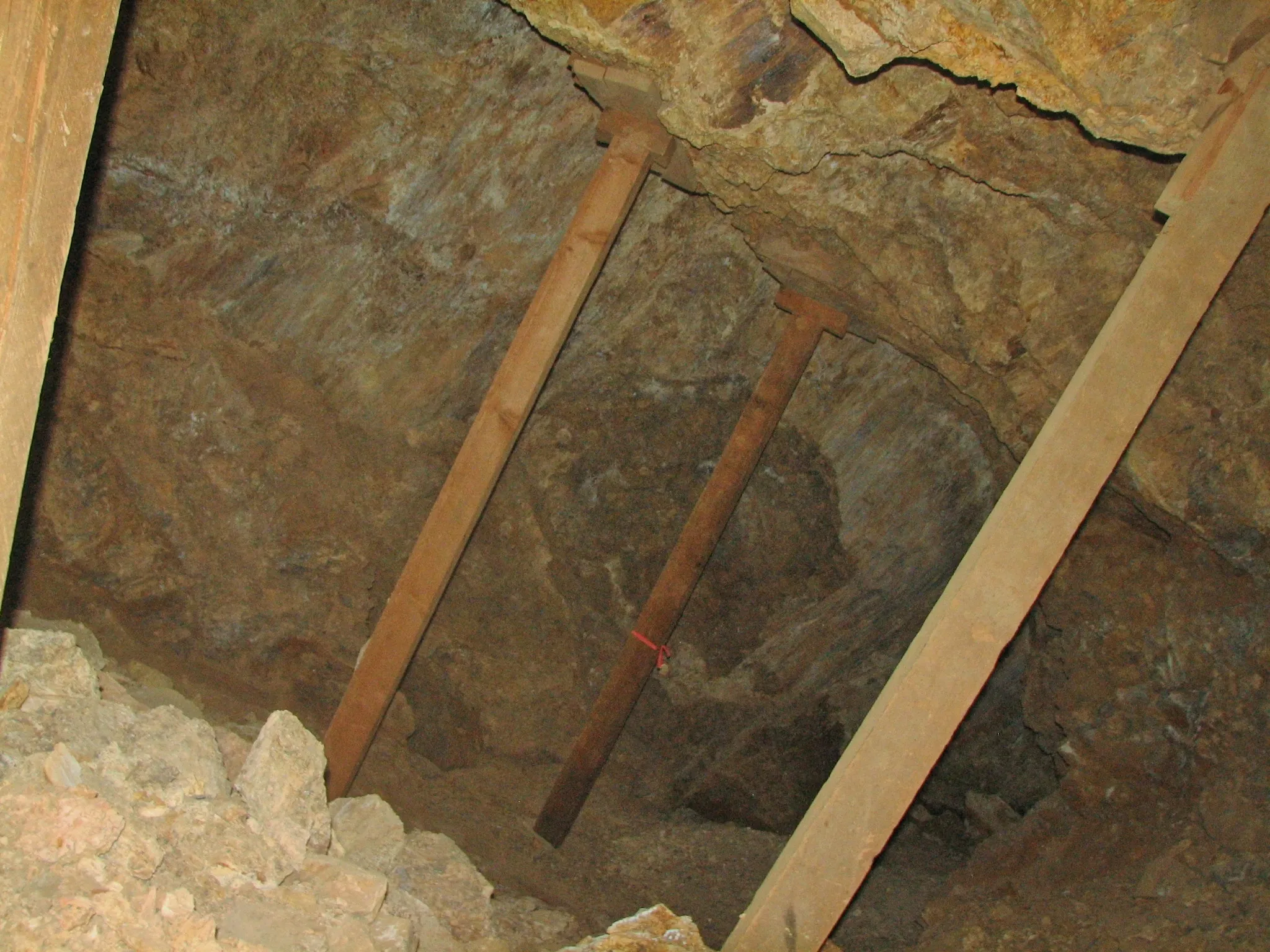 Diagonal timber posts propping up rocky mine ceiling corner.