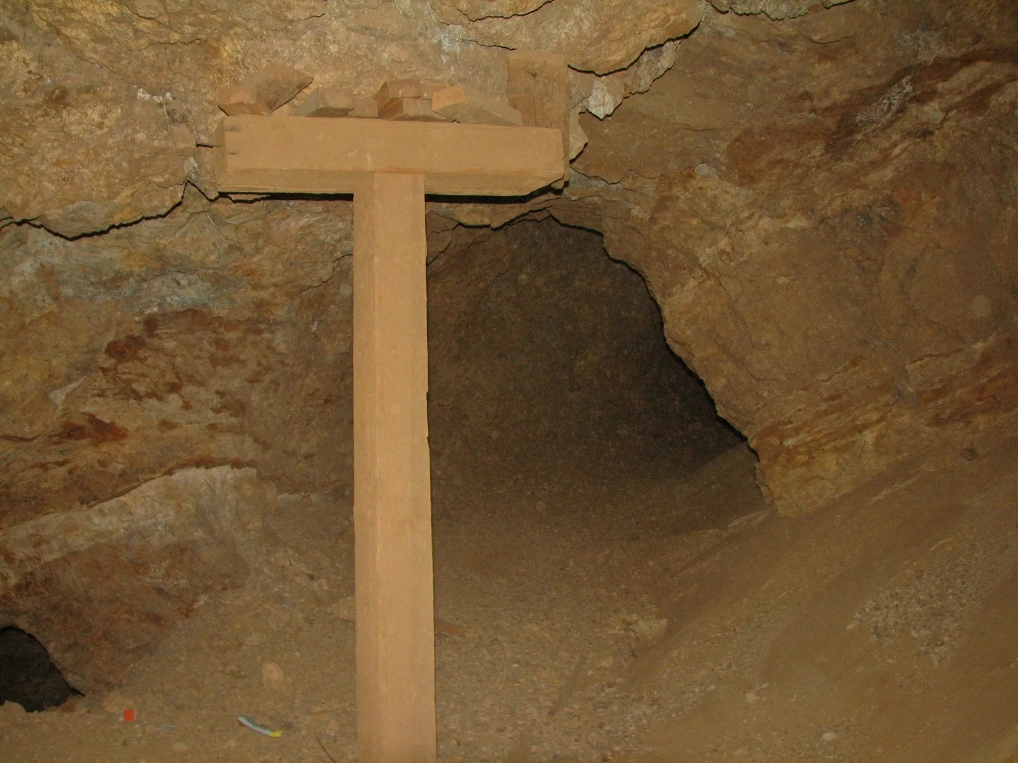 T-shaped wooden support post in dusty mine tunnel.