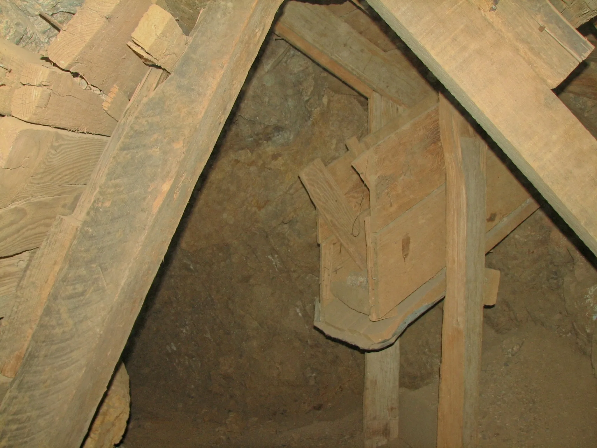 Wooden chute and support timbers inside rocky mine passage.