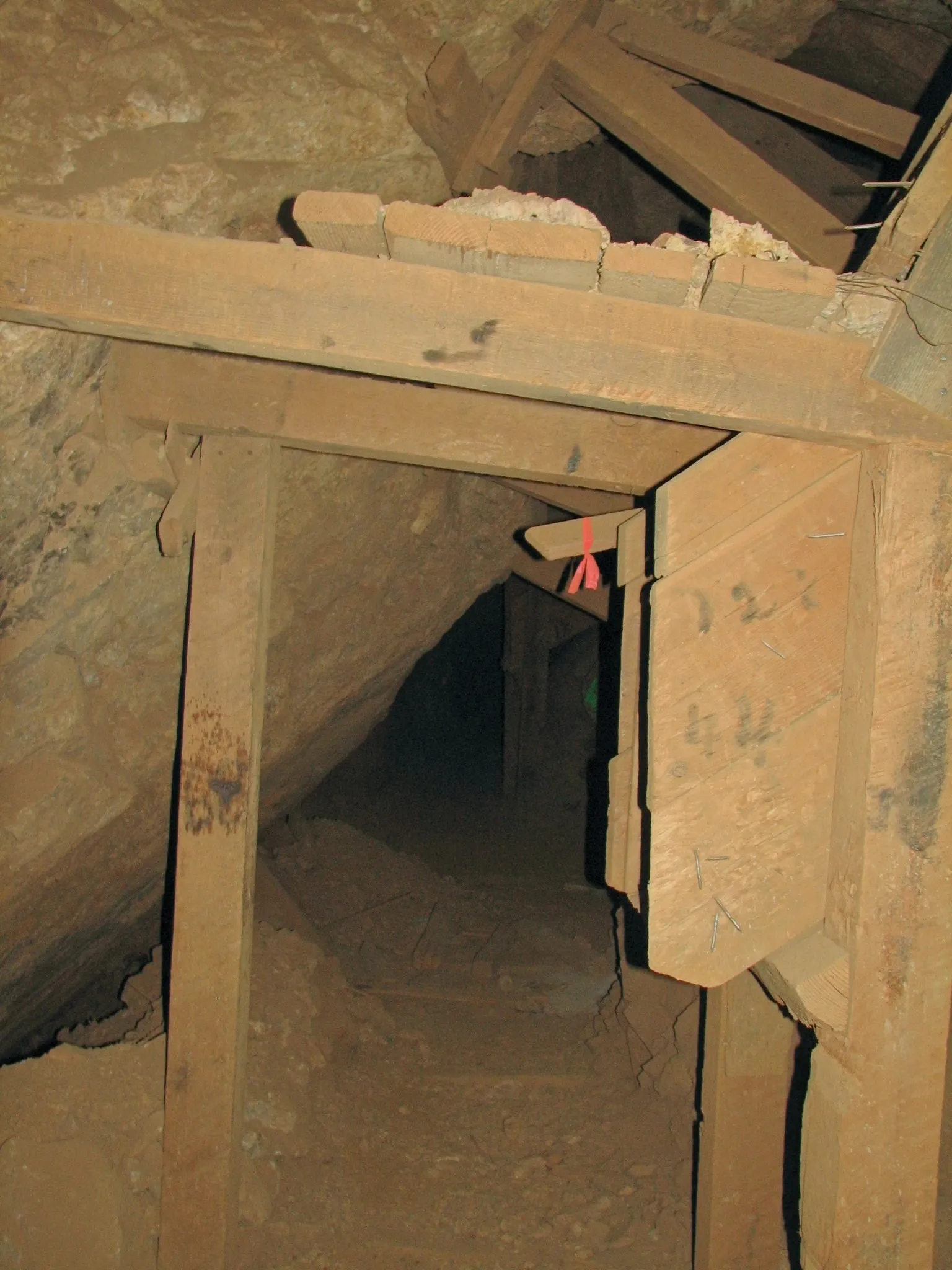 Timber-framed mine tunnel entrance with red ribbon on support brace.