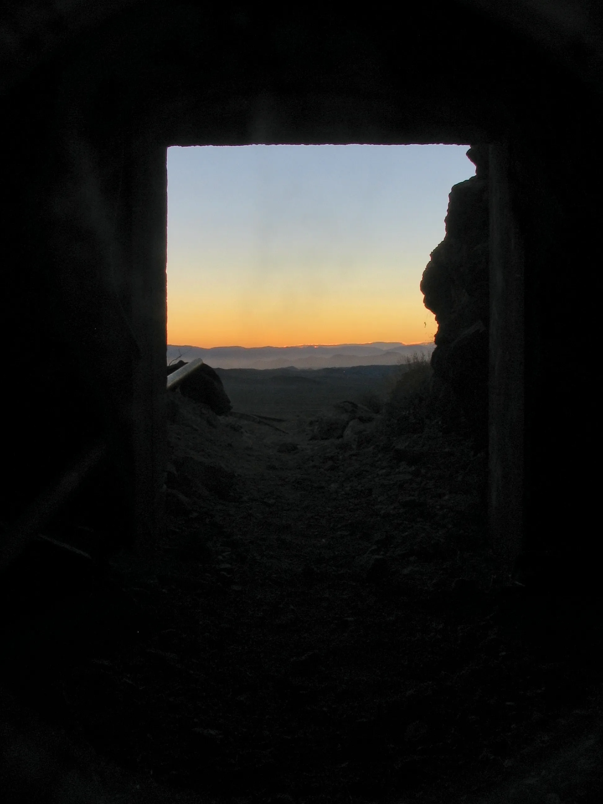 Dusk landscape framed by dark mine tunnel portal at War Eagle Mine.