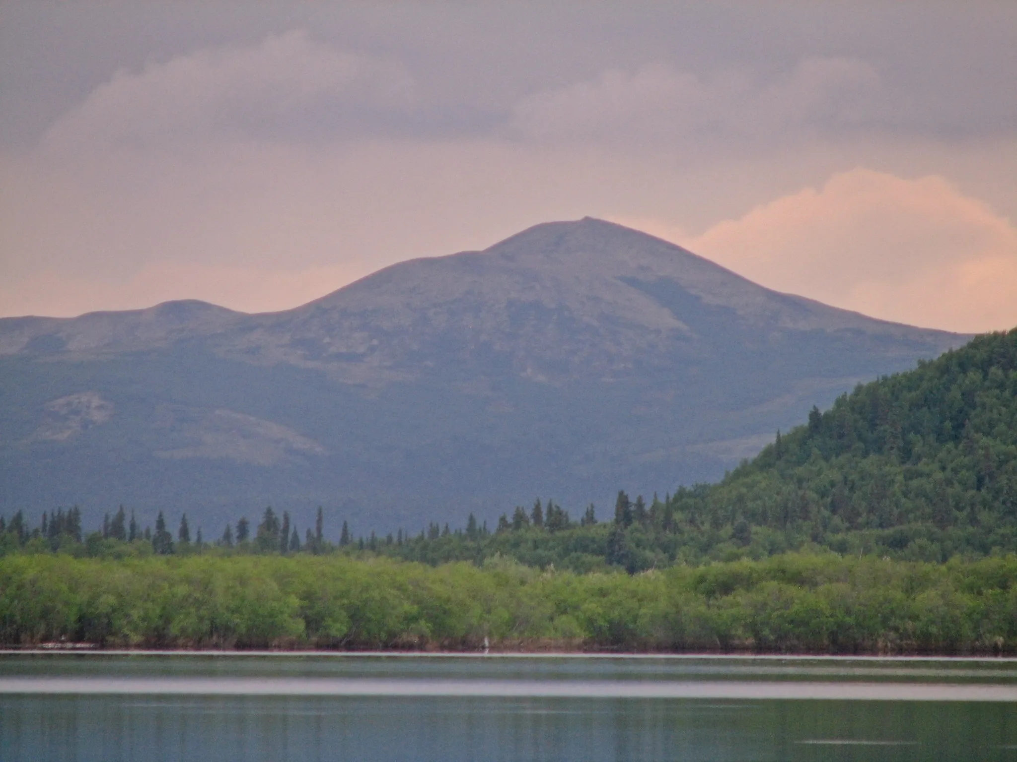 Rounded mountain above a calm lake at dusk in the Alaska wilderness near Kako.