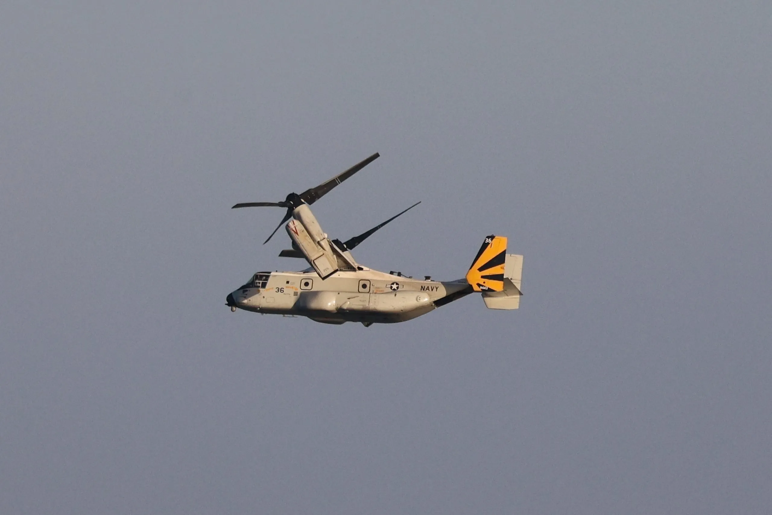US Navy V-22 Osprey in flight with rotors tilted upward near San Diego Bay, CA.