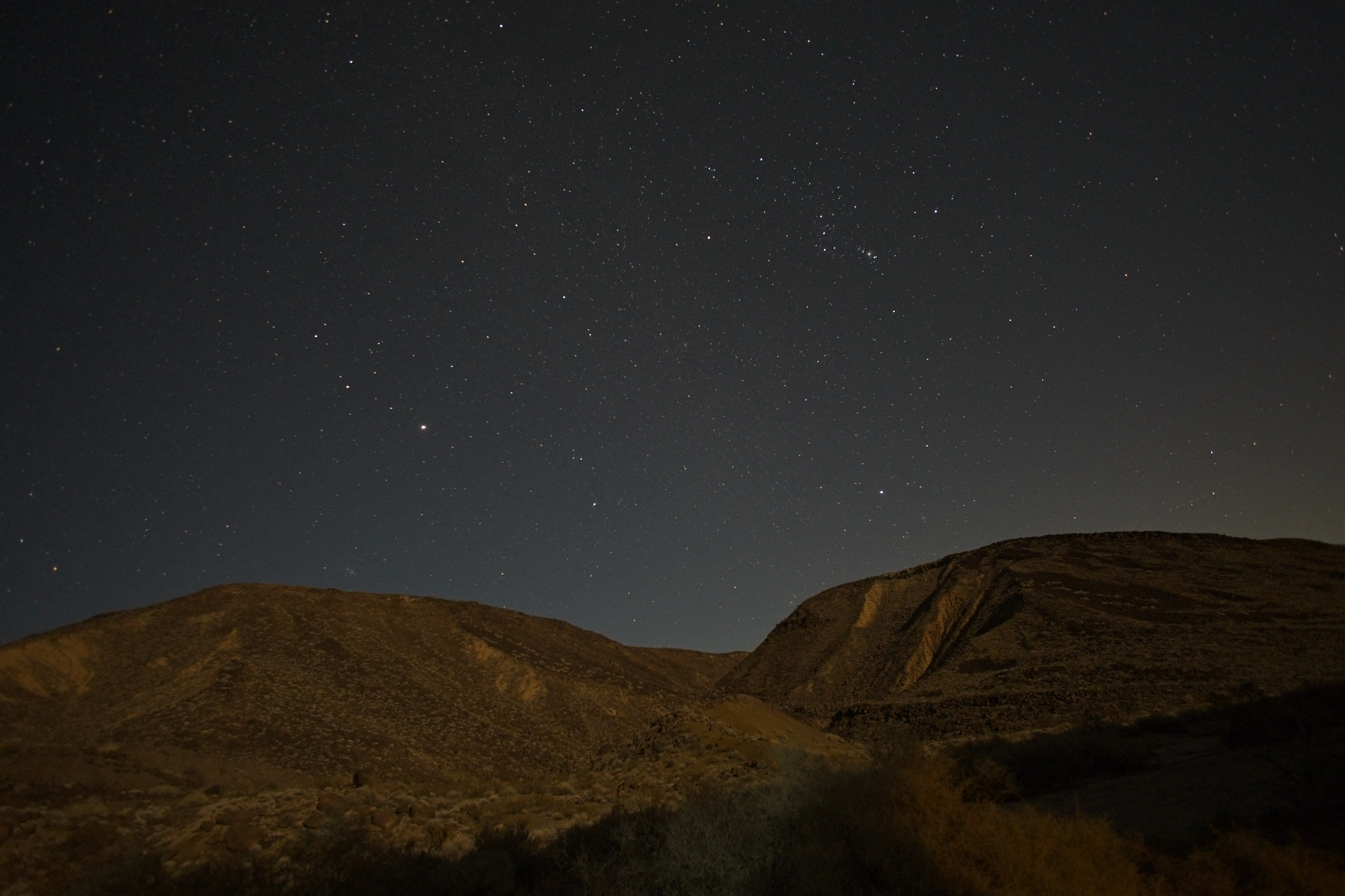 Dense star field above rugged desert hills in the Black Mountain Wilderness.