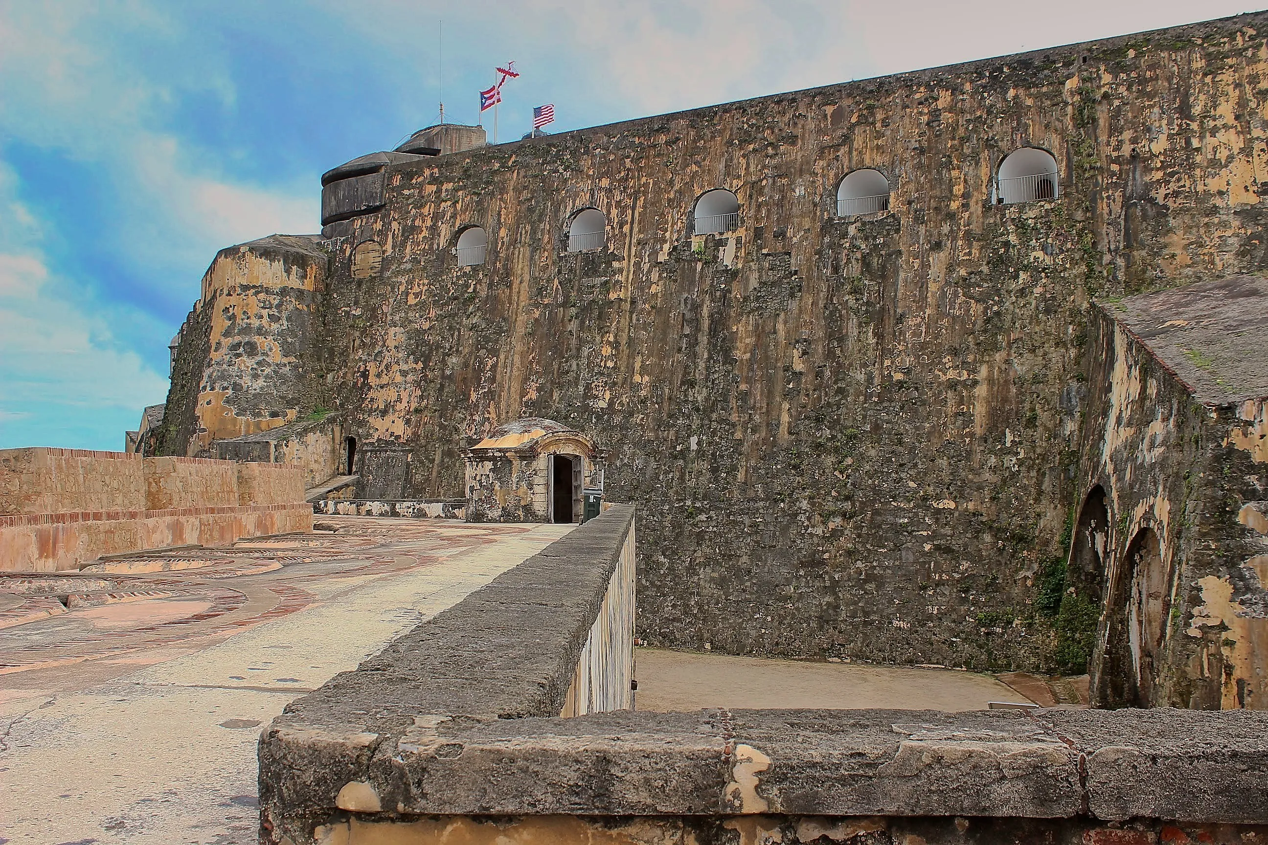 Massive stone walls and a garita terrace with flags atop Castillo San Felipe del Morro.