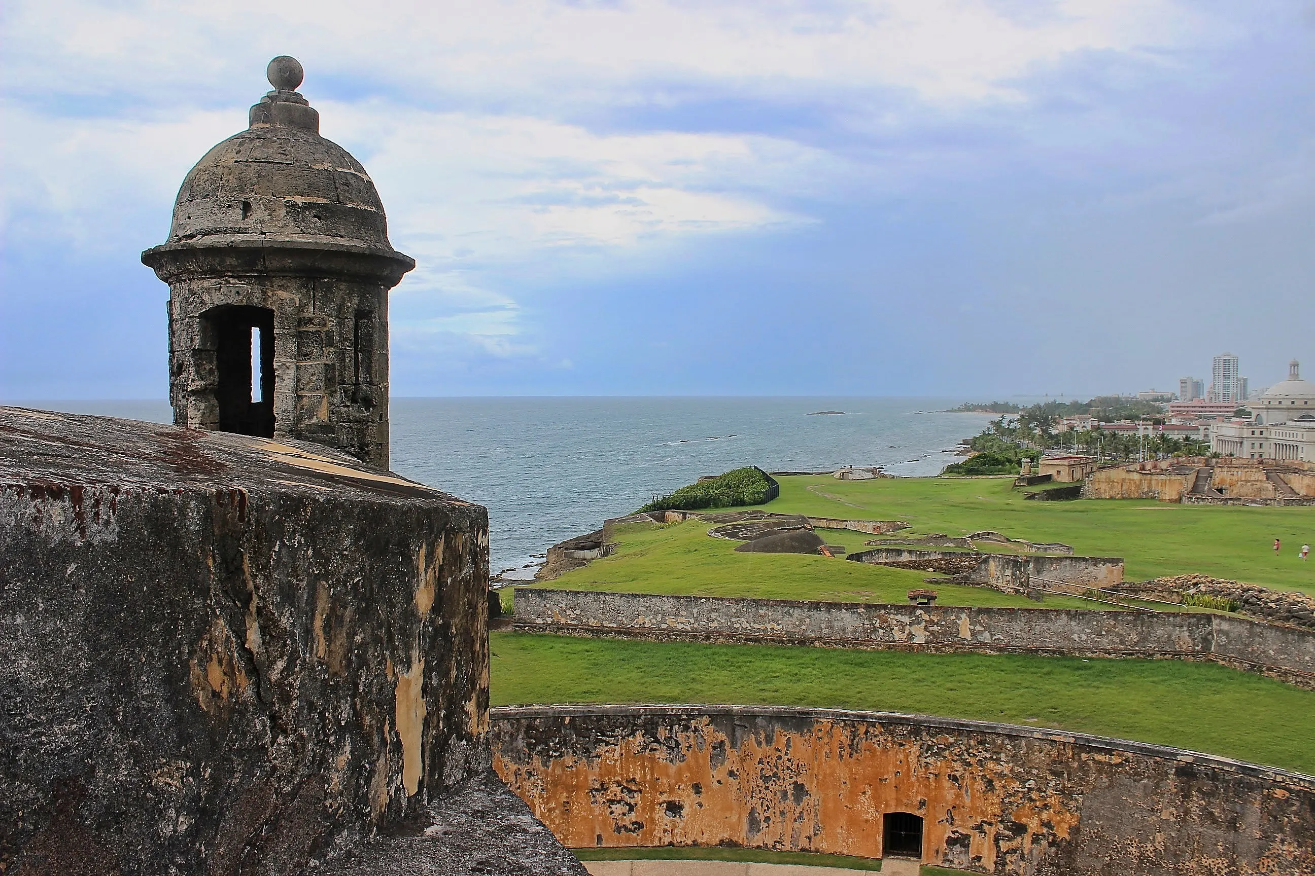 Stone garita and green glacis overlooking the ocean and San Juan skyline.