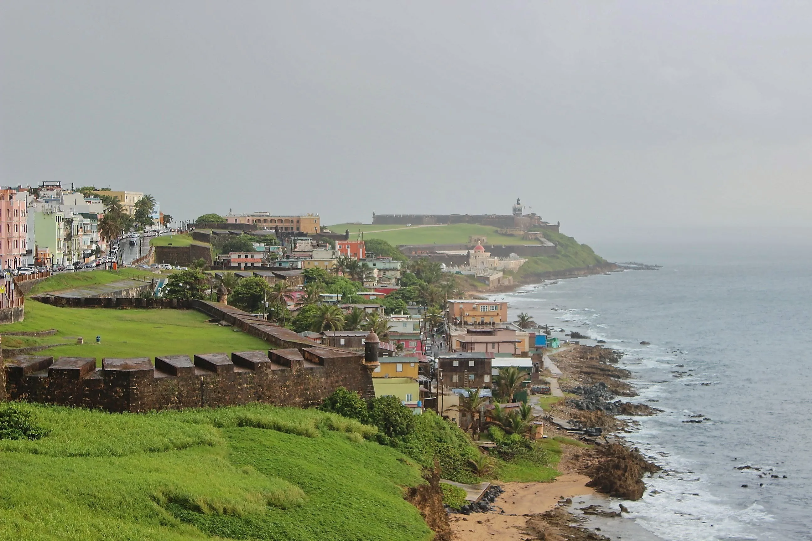 Old San Juan coastline with fort walls, La Perla, and El Morro in the distance.